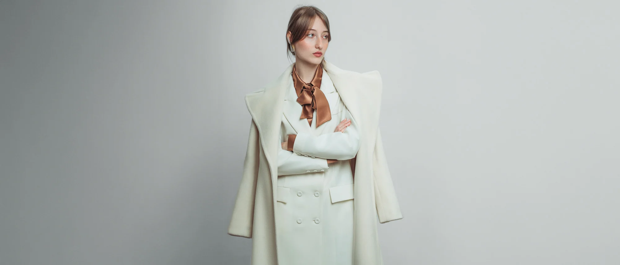 Incantevole Milano Fall Winter 2026–2027 – ivory tailoring and a draped coat against a pale studio backdrop